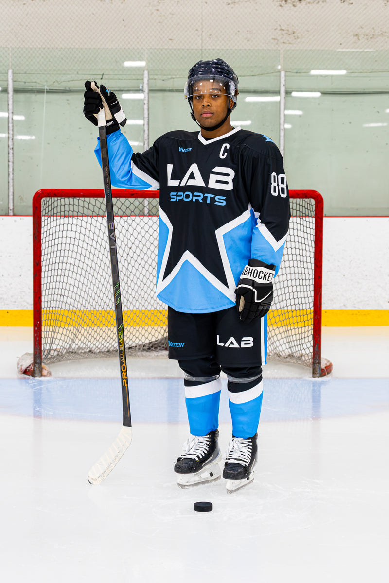 Joueur de hockey de la LHJMQ en équipement complet avec un bâton Pro All Black V2