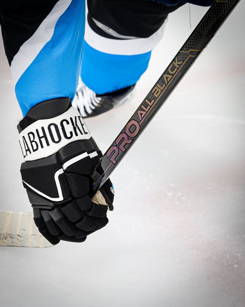 Gant d’un joueur de la LHJMQ tenant un bâton de hockey Pro All Black V2